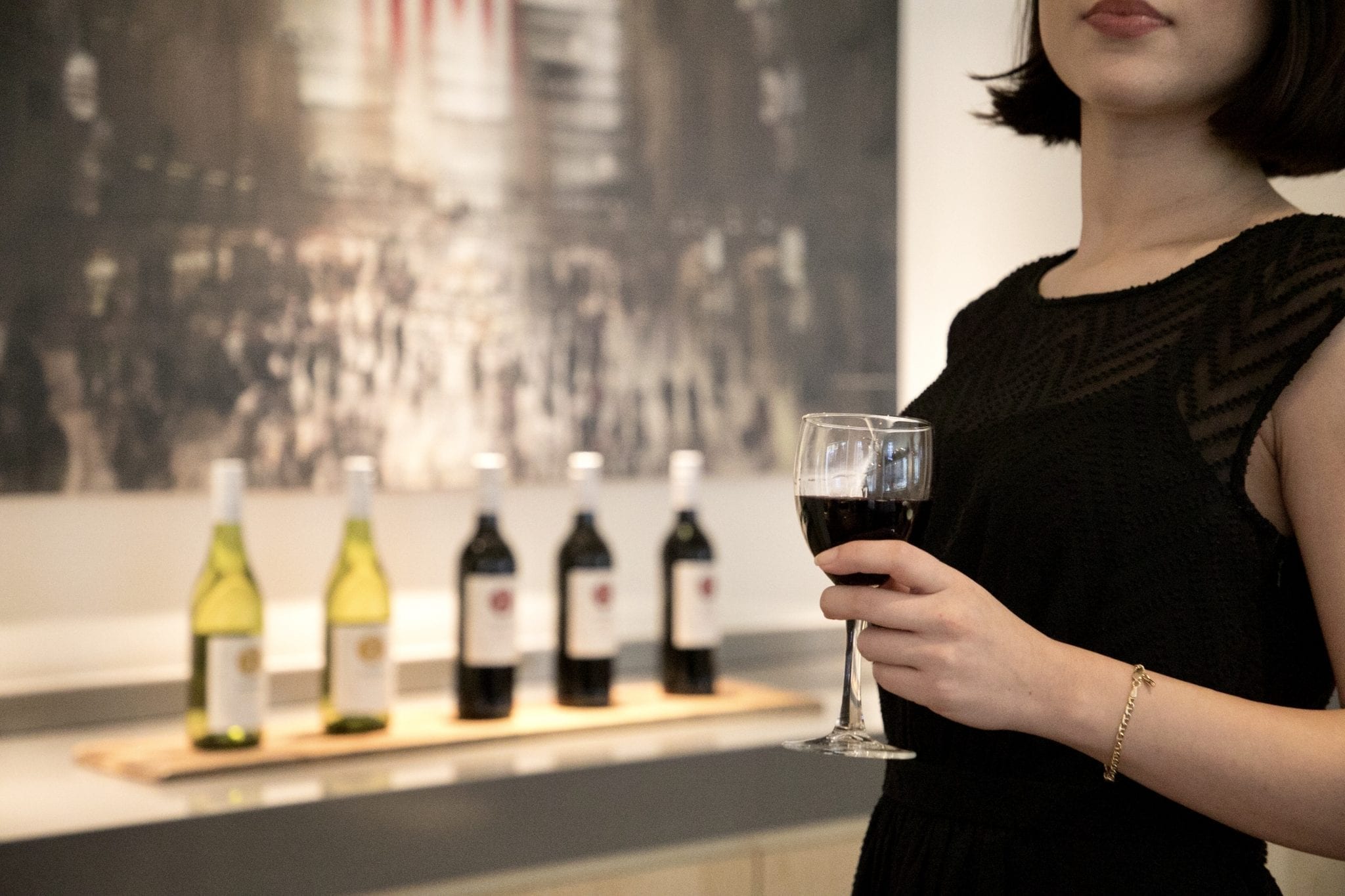 A host stands in front of wine bottles during a Social Sips event.