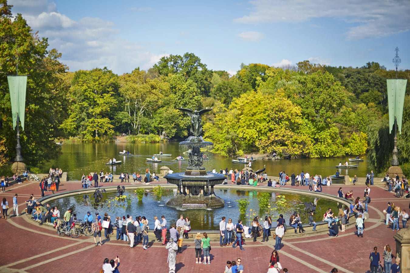 “Angel of the Waters” fountain from above. Many tourists and people are standing or sitting along this Central Park fountain.
